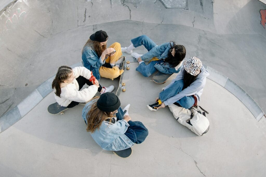 Group of young skateboarders sitting and chatting at a skatepark, captured from above.