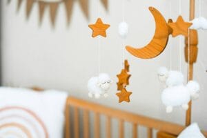 Wooden crib mobile featuring stars, a crescent moon, and fluffy sheep for a cozy baby nursery.